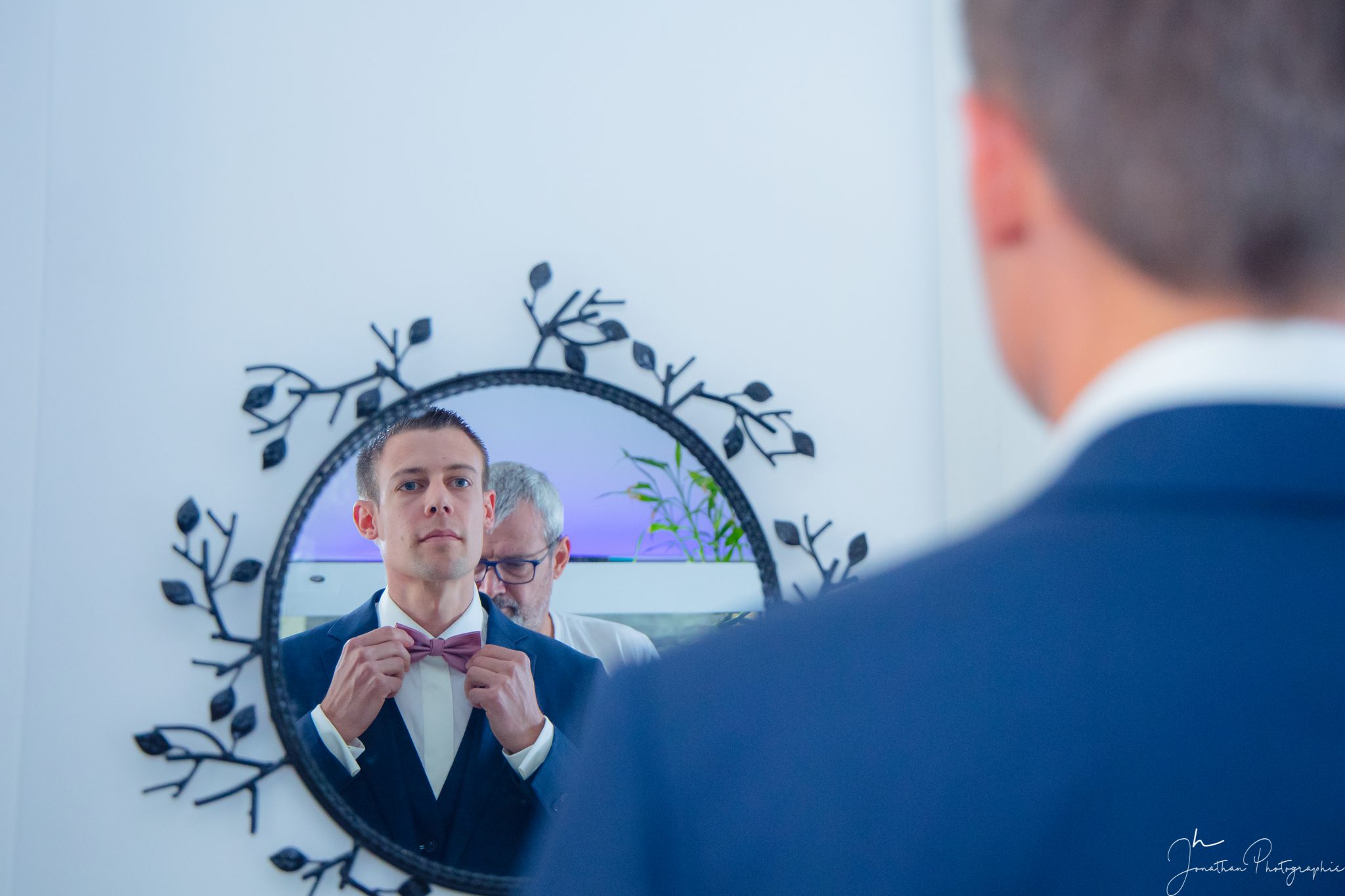 Photo du marié qui finalise sa tenue face au miroir